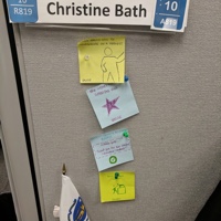 A cubical wall with a name tag and post its.