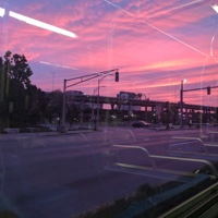 A pink sunset through the windows of a bus