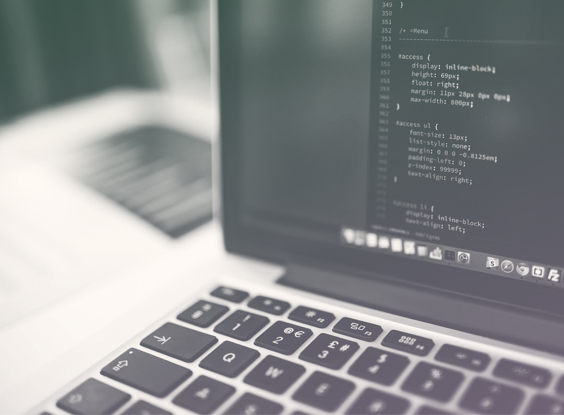 A computer screen with CSS code displayed on a sleek white desk.