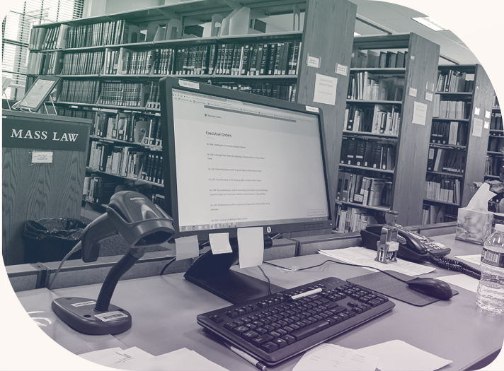 A computer in a Massachusetts Law library surrounded by bookcases and papers, with Mass.gov loaded on the screen.